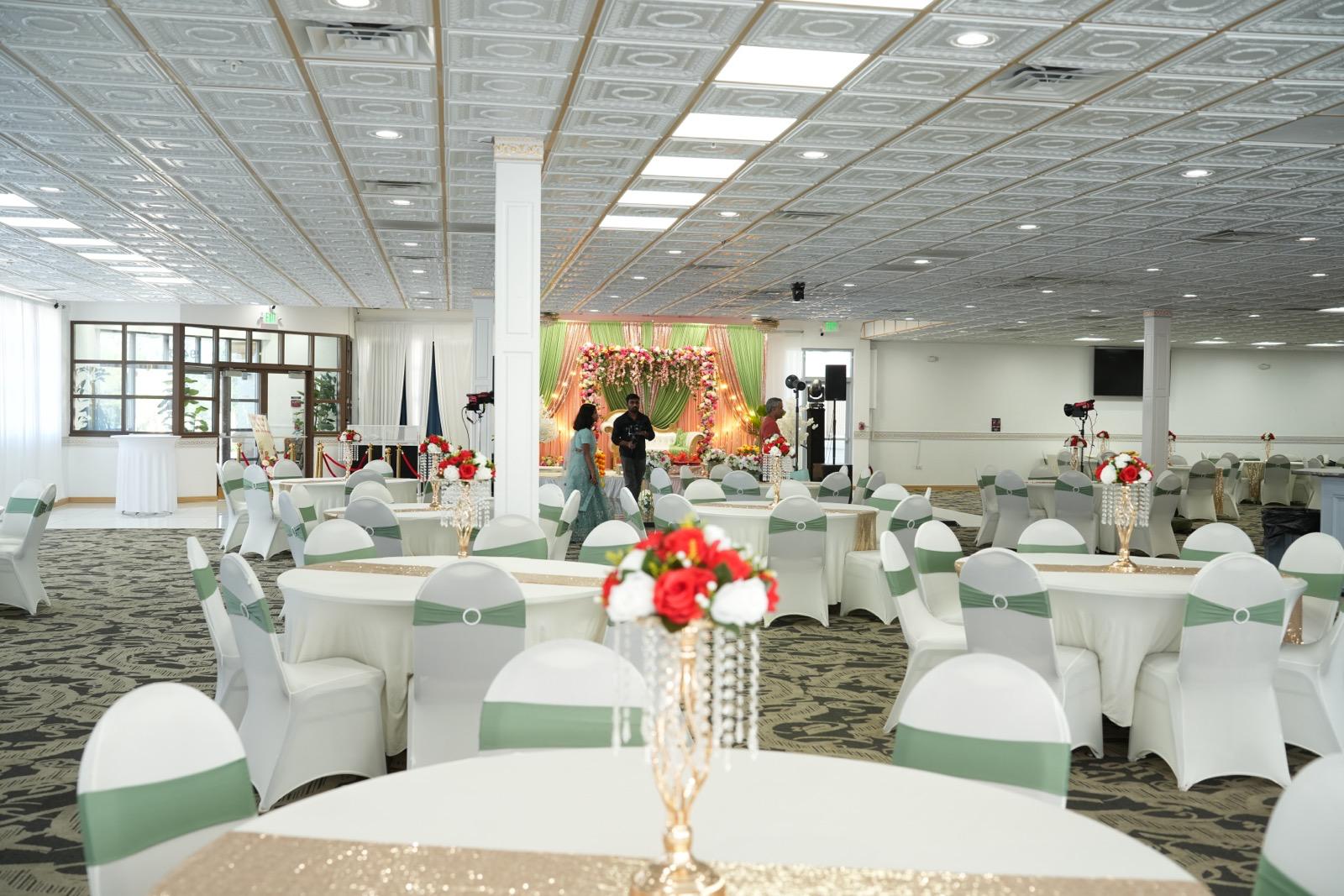 Meadows banquet hall with round tables, white chairs and gold centerpieces