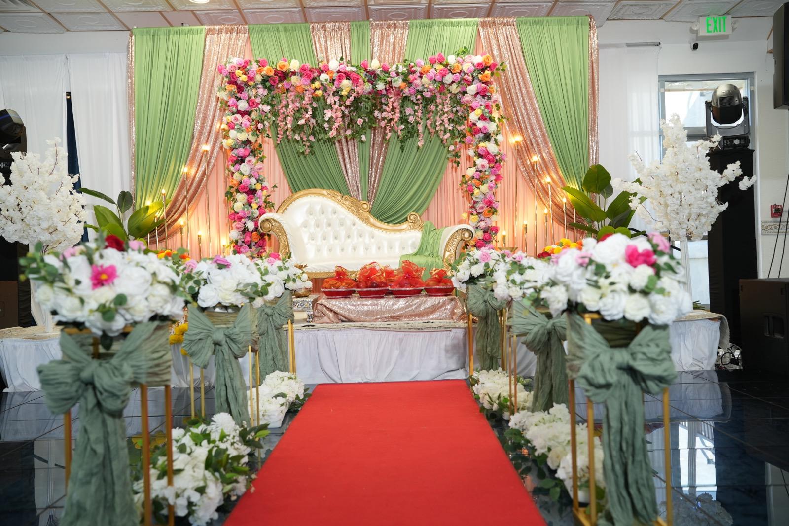 Floral wedding stage with sage rose-gold drapes, white-gold sofa and red carpet