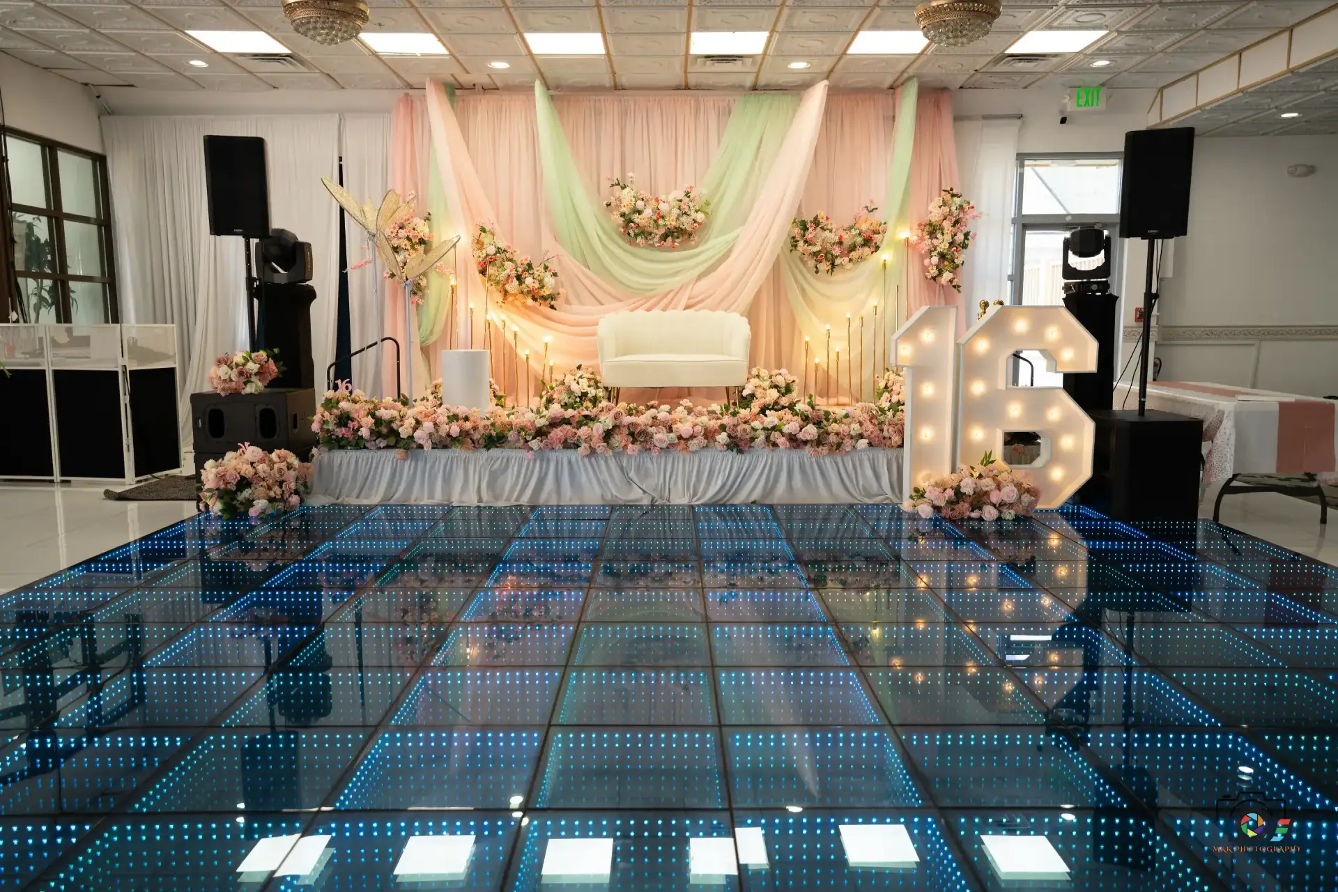 Reception with lit dance floor and floral stage